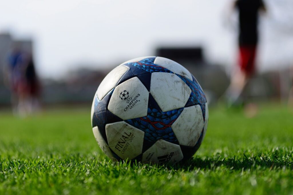 pexels photo 16499021 Focus on a soccer ball resting on a vibrant green sports field under daylight.