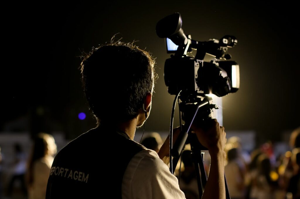 pexels photo 2883160 A cameraman filming an event outdoors at night with professional equipment, capturing the vibrant atmosphere.