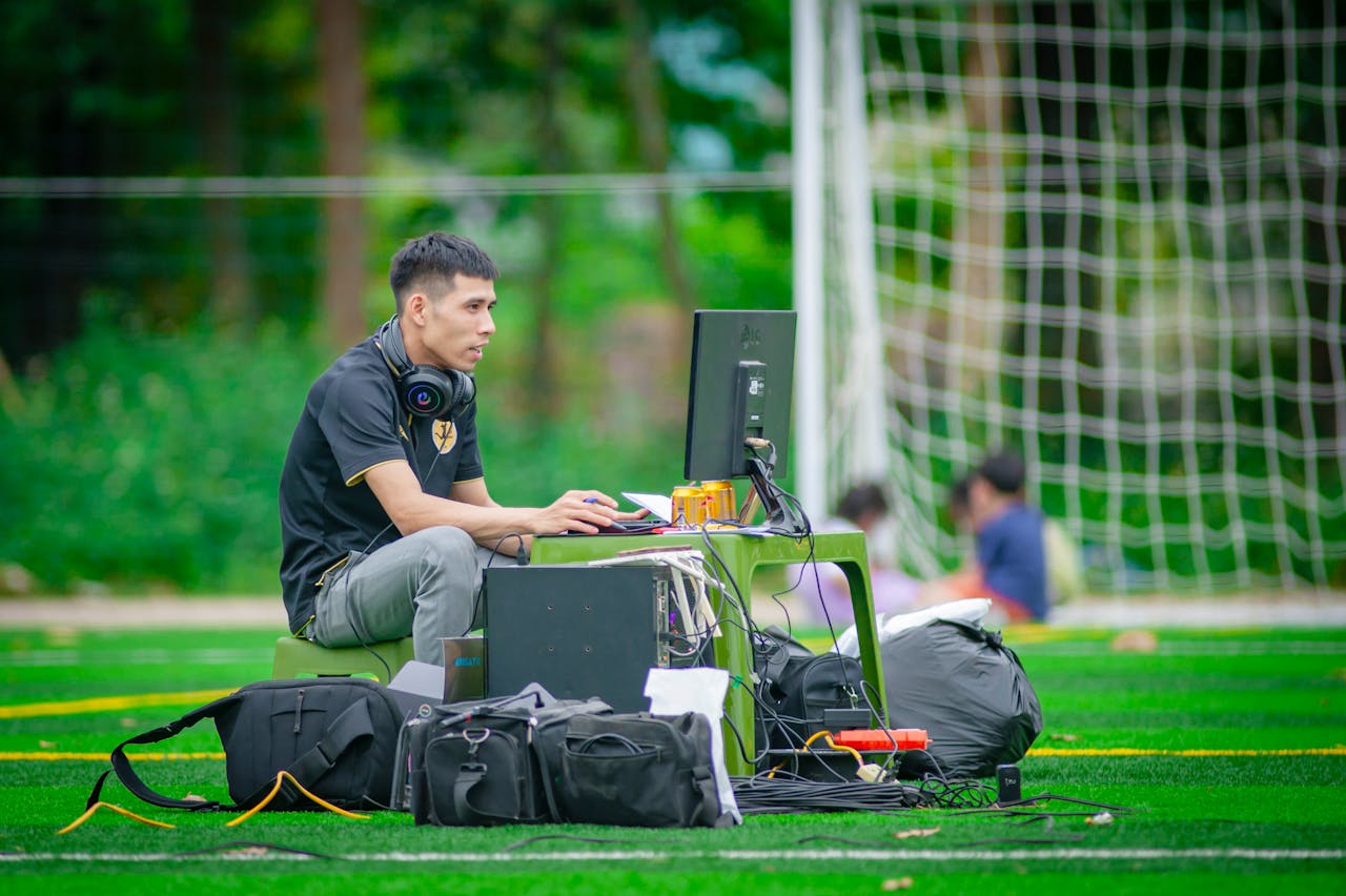 services-02 Man working at a computer setup on a football field in Hanoi, Vietnam.