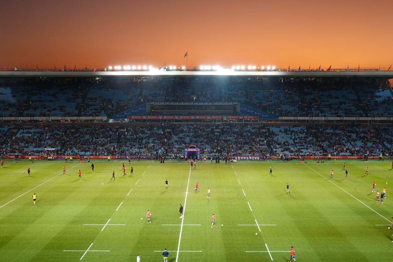 services-02 Exciting rugby game unfolding under stunning sunset in large stadium.